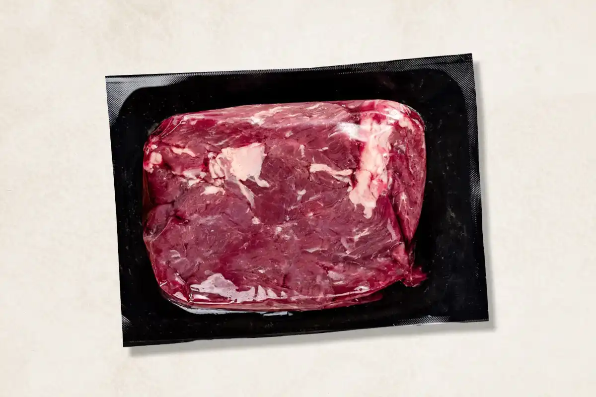 Packaged steak tips on beige background